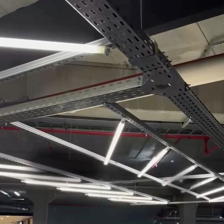Eletrocalhas perfuradas e luminárias instaladas no teto de uma garagem.